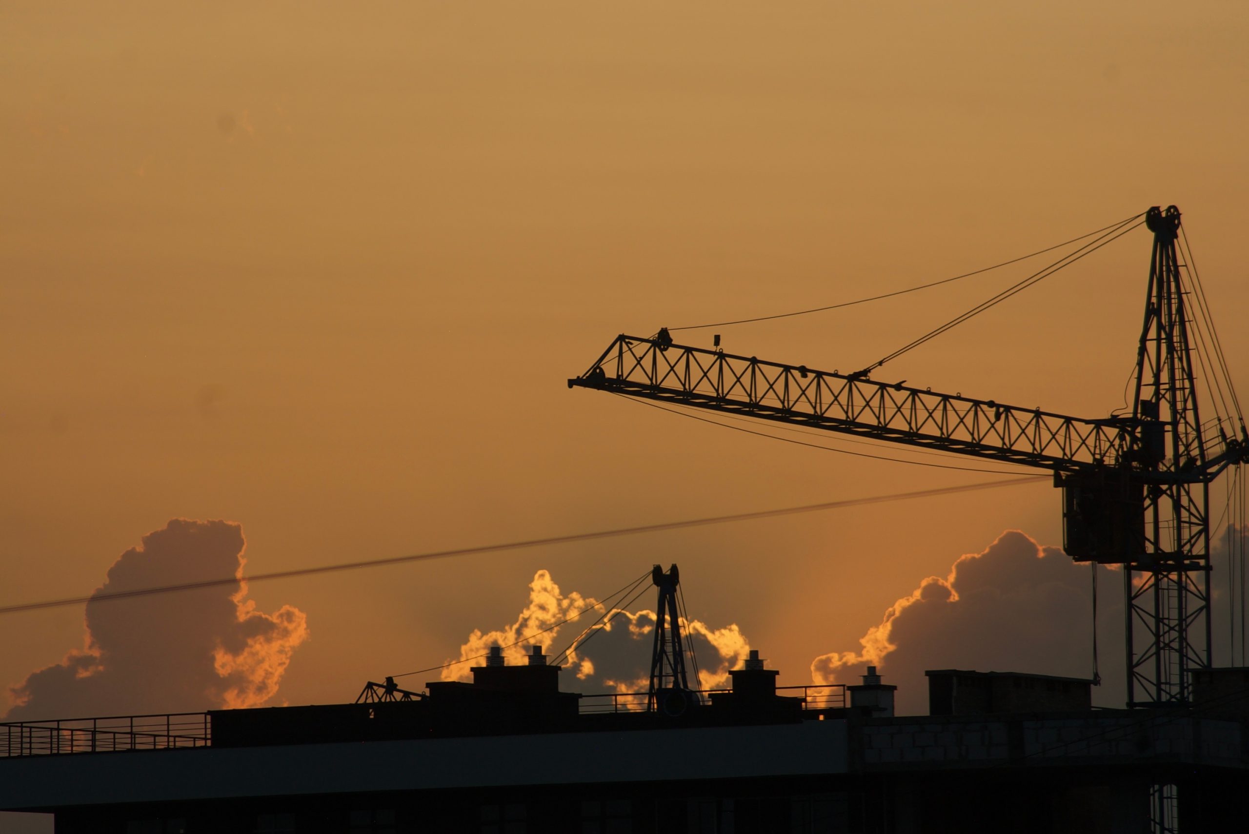 Construction crane and city skyline at sunset representing commercial property insurance trends in Sonora, CA.